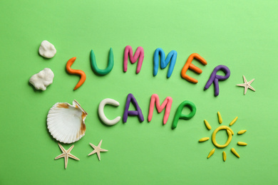 Flat lay composition with phrase SUMMER CAMP made of modelling clay on green background