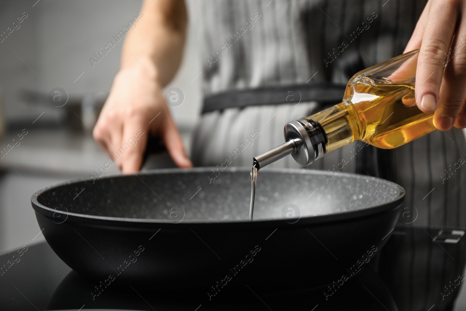 Photo of Woman pouring cooking oil from bottle into frying pan, closeup