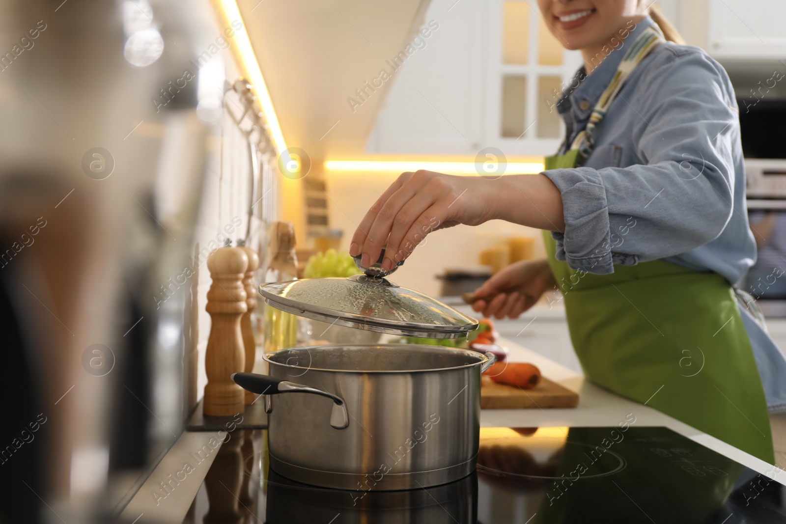 Photo of Woman opening pot with fresh bouillon in kitchen, closeup. Homemade recipe