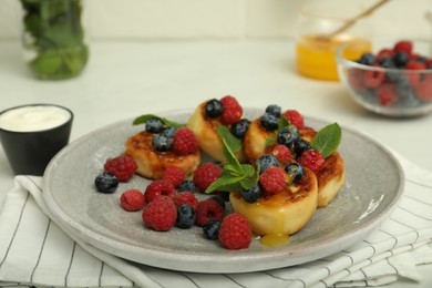 Photo of Delicious cottage cheese pancakes with fresh berries and mint on white table