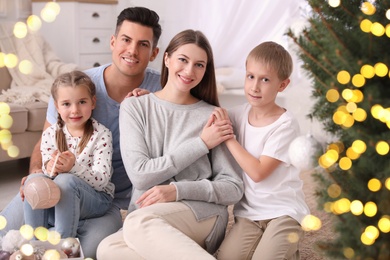 Photo of Happy family with cute children near Christmas tree together at home