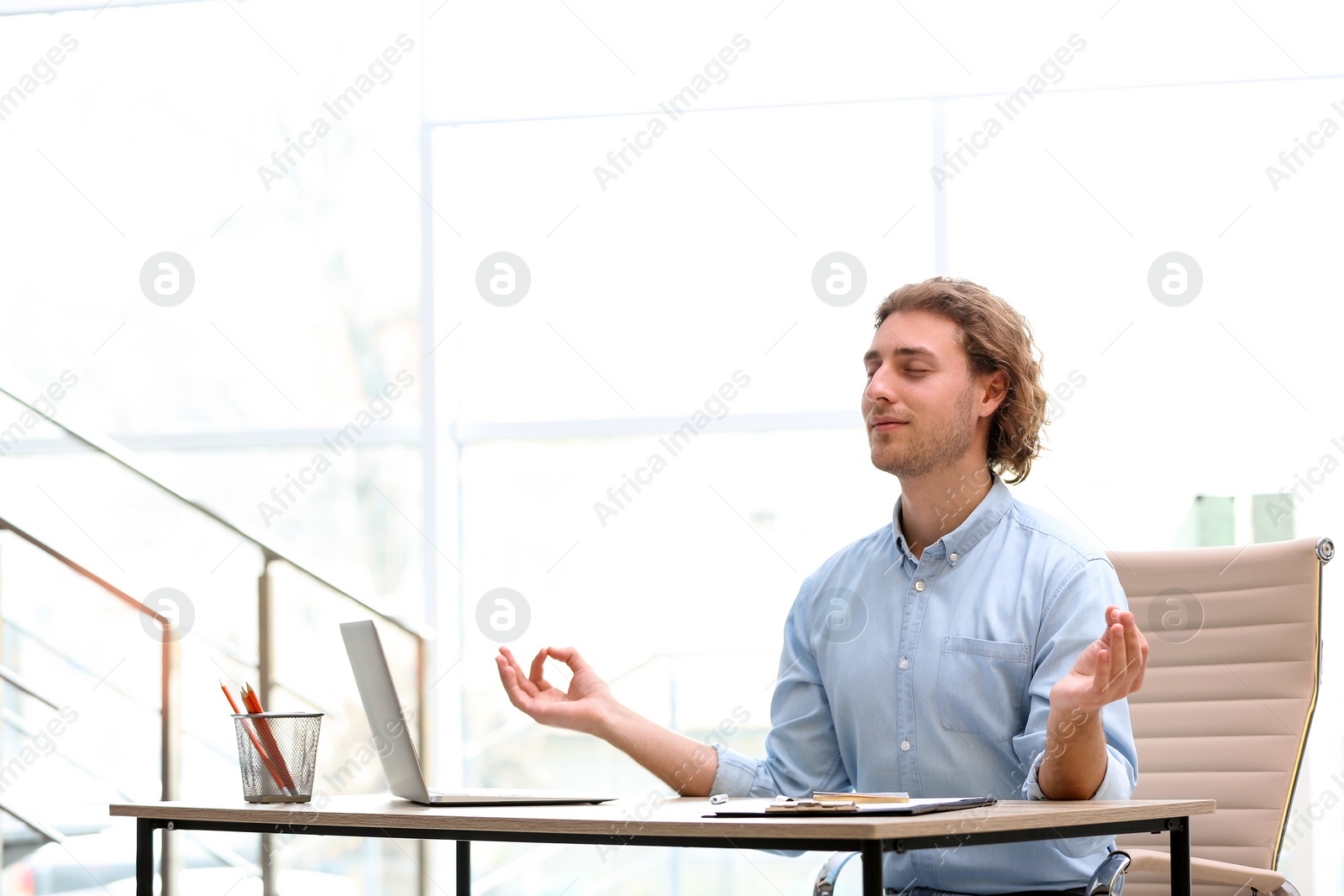 Photo of Young businessman meditating at table in office during break, space for text. Zen yoga