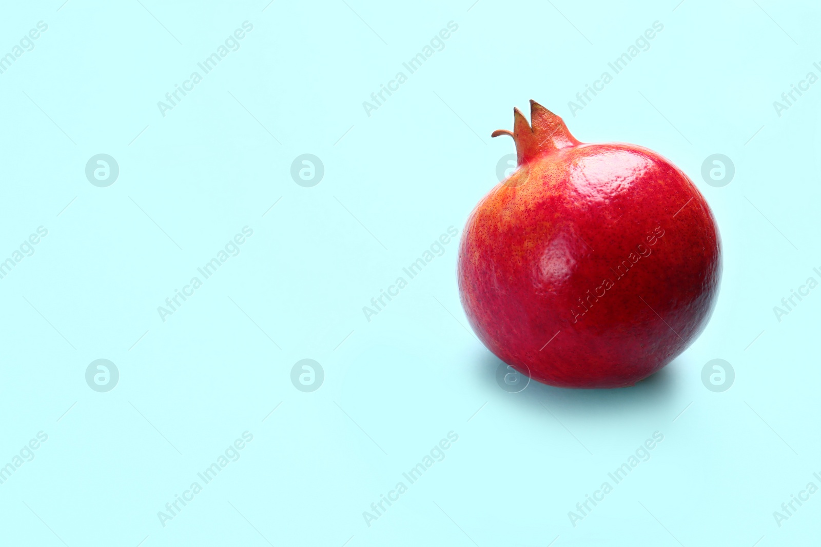 Photo of Tasty raw pomegranate on blue background, space for text