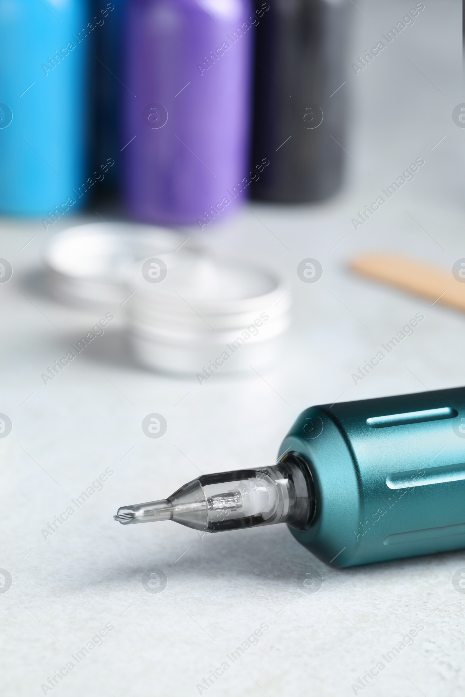 Photo of Modern professional tattoo machine on white table, closeup