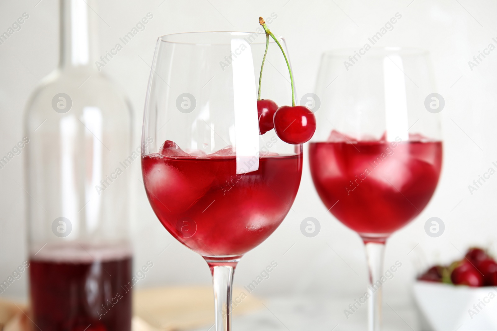 Photo of Delicious cherry wine with ripe juicy berries on light background, closeup