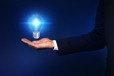 Image of Idea concept. Businessman with glowing light bulb on dark background, closeup