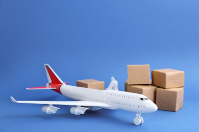 Photo of Airplane model and carton boxes on blue background. Courier service