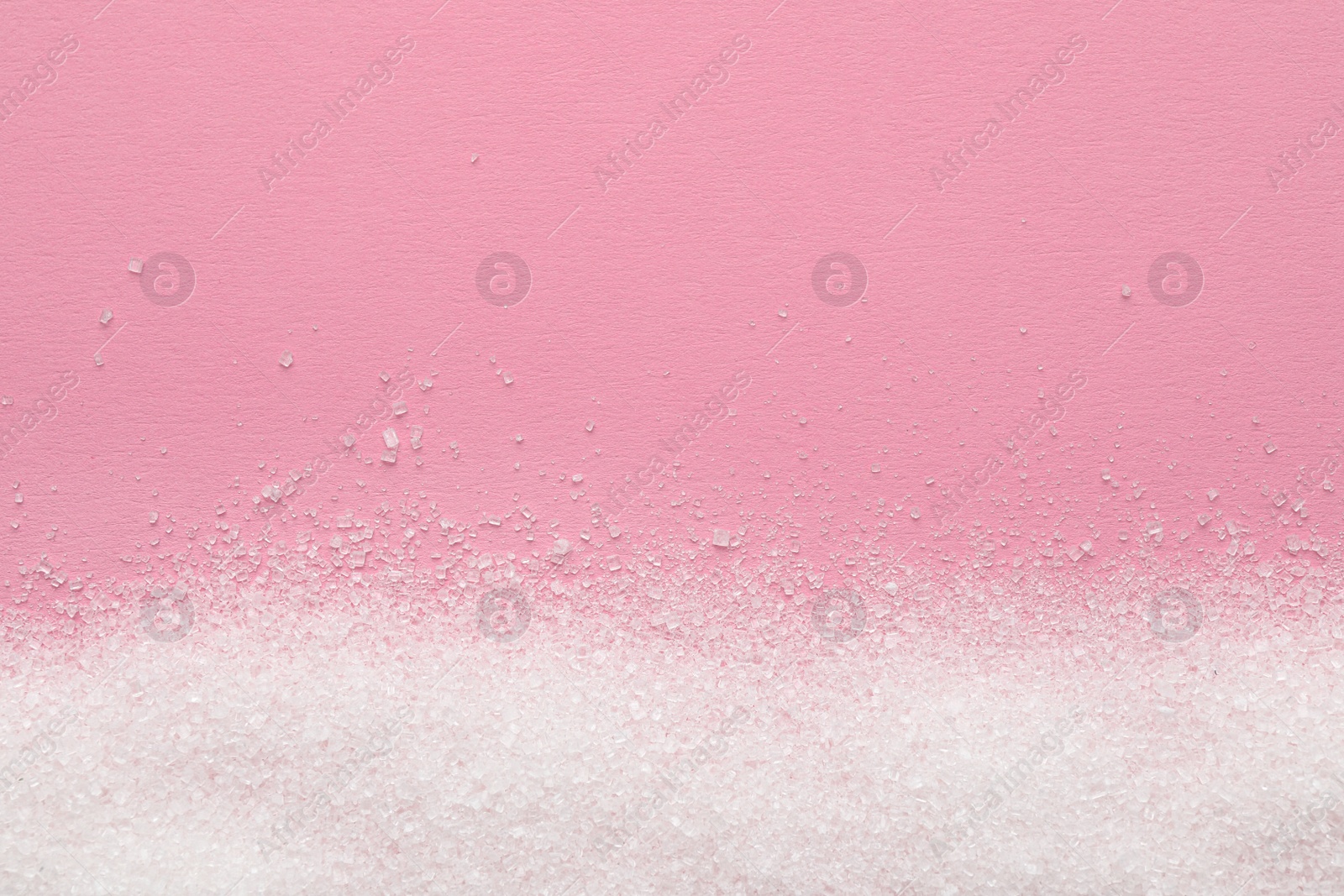 Photo of Granulated sugar on pink background, top view. Space for text