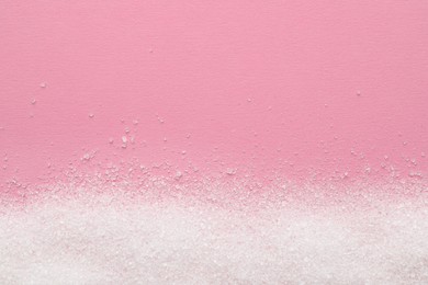 Photo of Granulated sugar on pink background, top view. Space for text