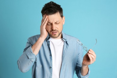 Photo of Man suffering from terrible migraine on light blue background