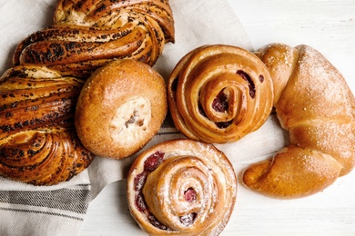 Different delicious fresh pastries on white wooden background, flat lay