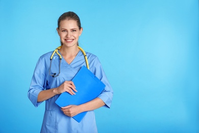 Photo of Portrait of young medical assistant with stethoscope and clipboard on color background. Space for text