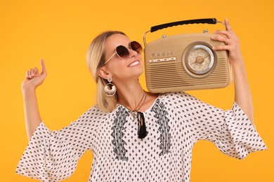 Photo of Portrait of happy hippie woman with retro radio receiver on yellow background