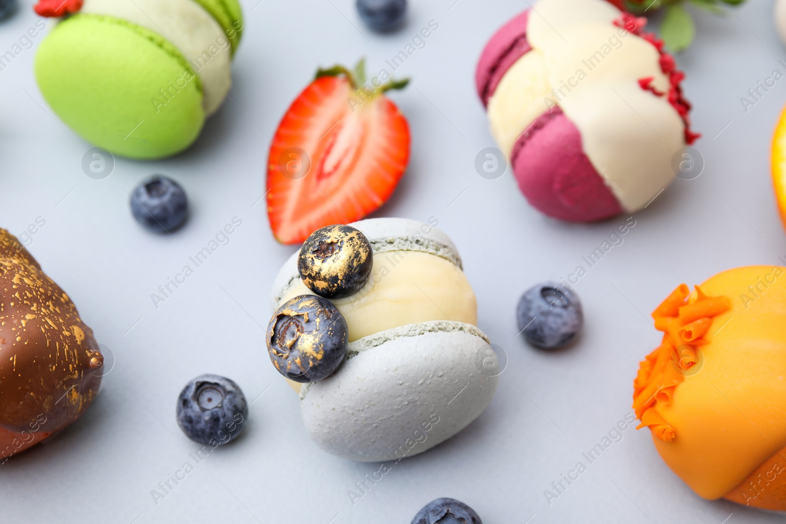 Photo of Delicious macarons and berries on light blue table, closeup