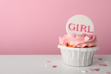Photo of Baby shower cupcake with Girl topper on white table against pink background, space for text