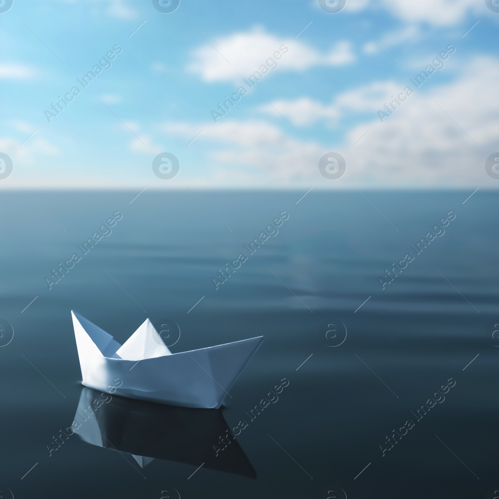 Image of White paper boat floating on calm sea 