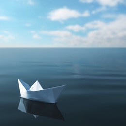 Image of White paper boat floating on calm sea 