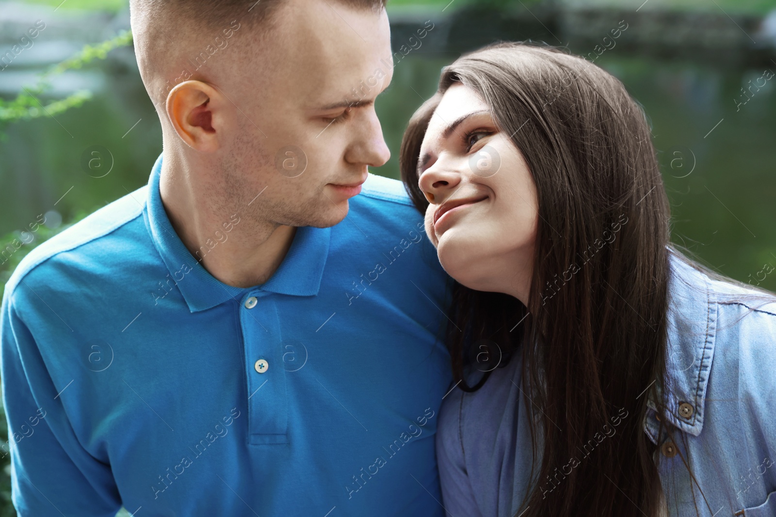 Photo of Affectionate young couple sitting together in park, closeup