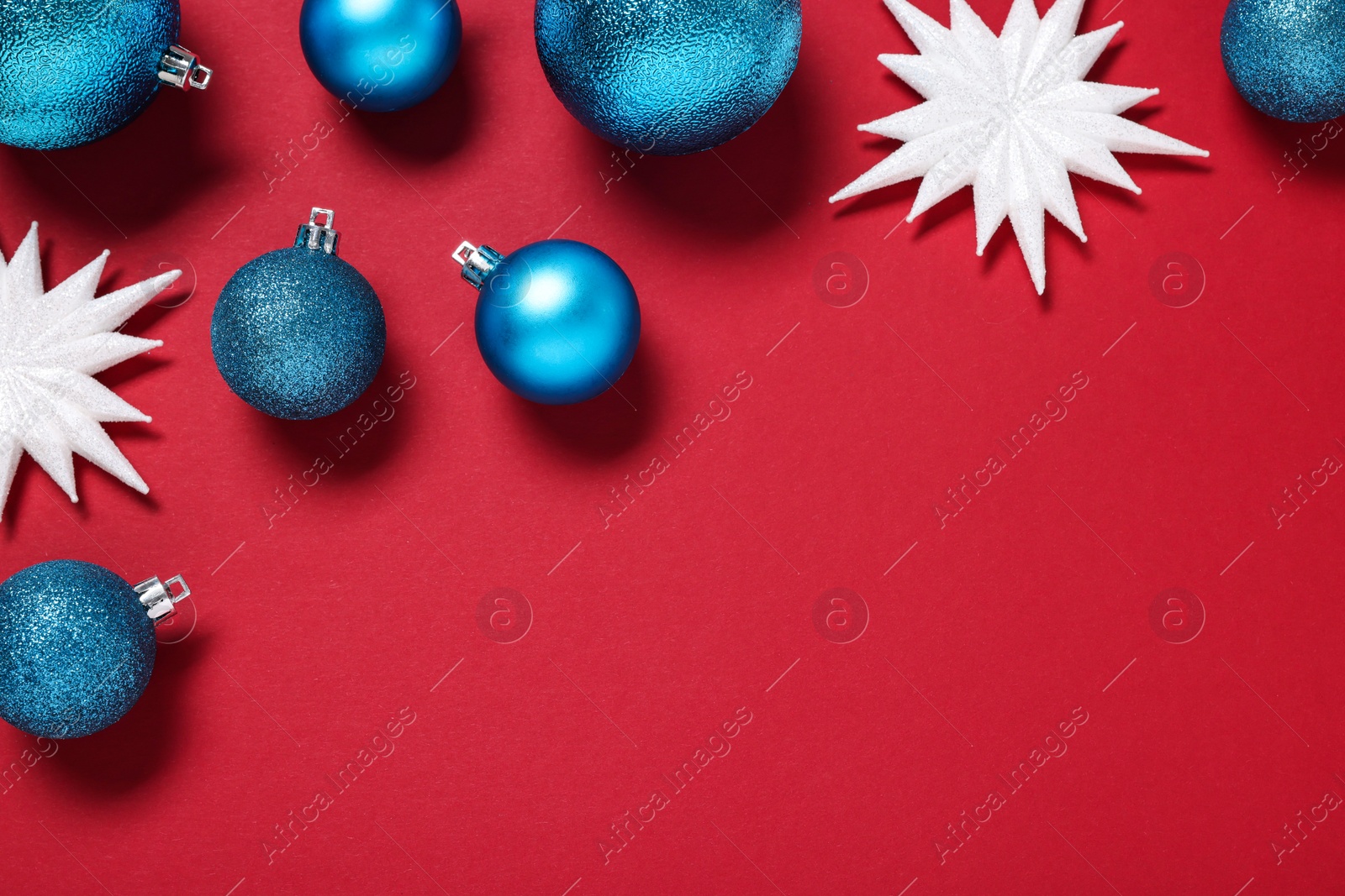 Photo of Christmas balls and decorative snowflakes on red background, flat lay. Space for text