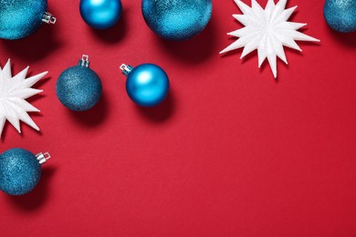 Christmas balls and decorative snowflakes on red background, flat lay. Space for text