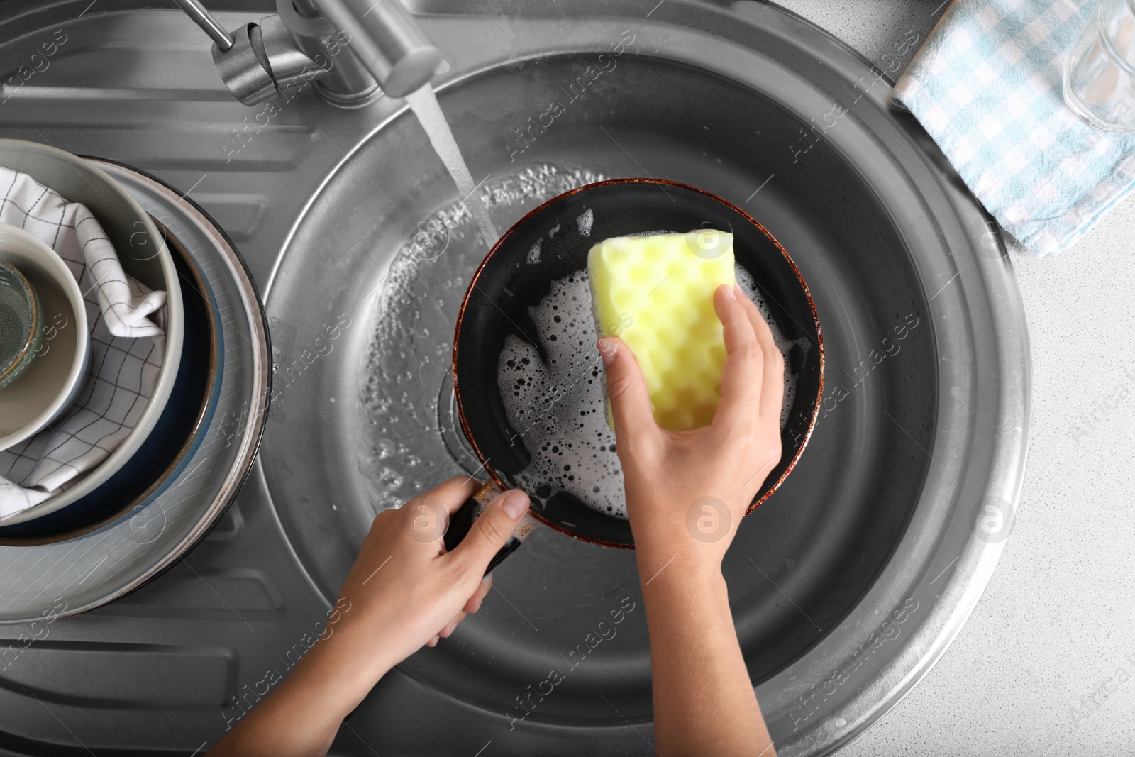 Photo of Woman washing dirty frying pan in sink, above view