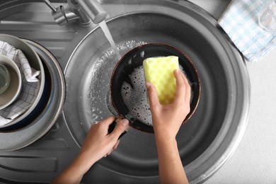 Photo of Woman washing dirty frying pan in sink, above view