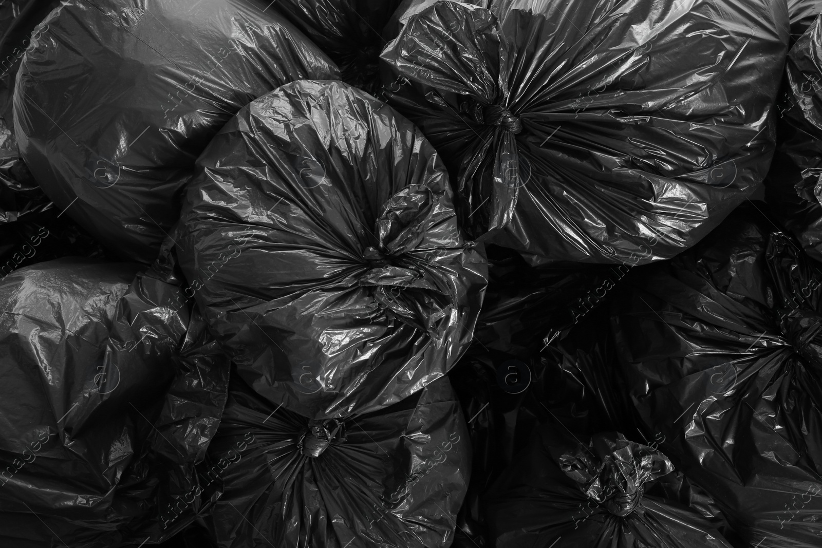 Photo of Black trash bags full of garbage as background, top view