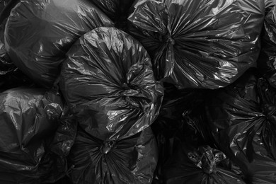 Photo of Black trash bags full of garbage as background, top view