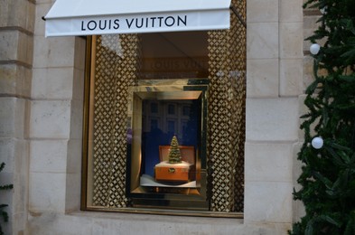 Photo of Paris, France - December 10, 2022: Louis Vuitton window store display with decorative suitcase and Christmas tree