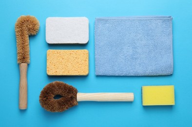 Photo of Many different sponges and other cleaning products on light blue background, flat lay