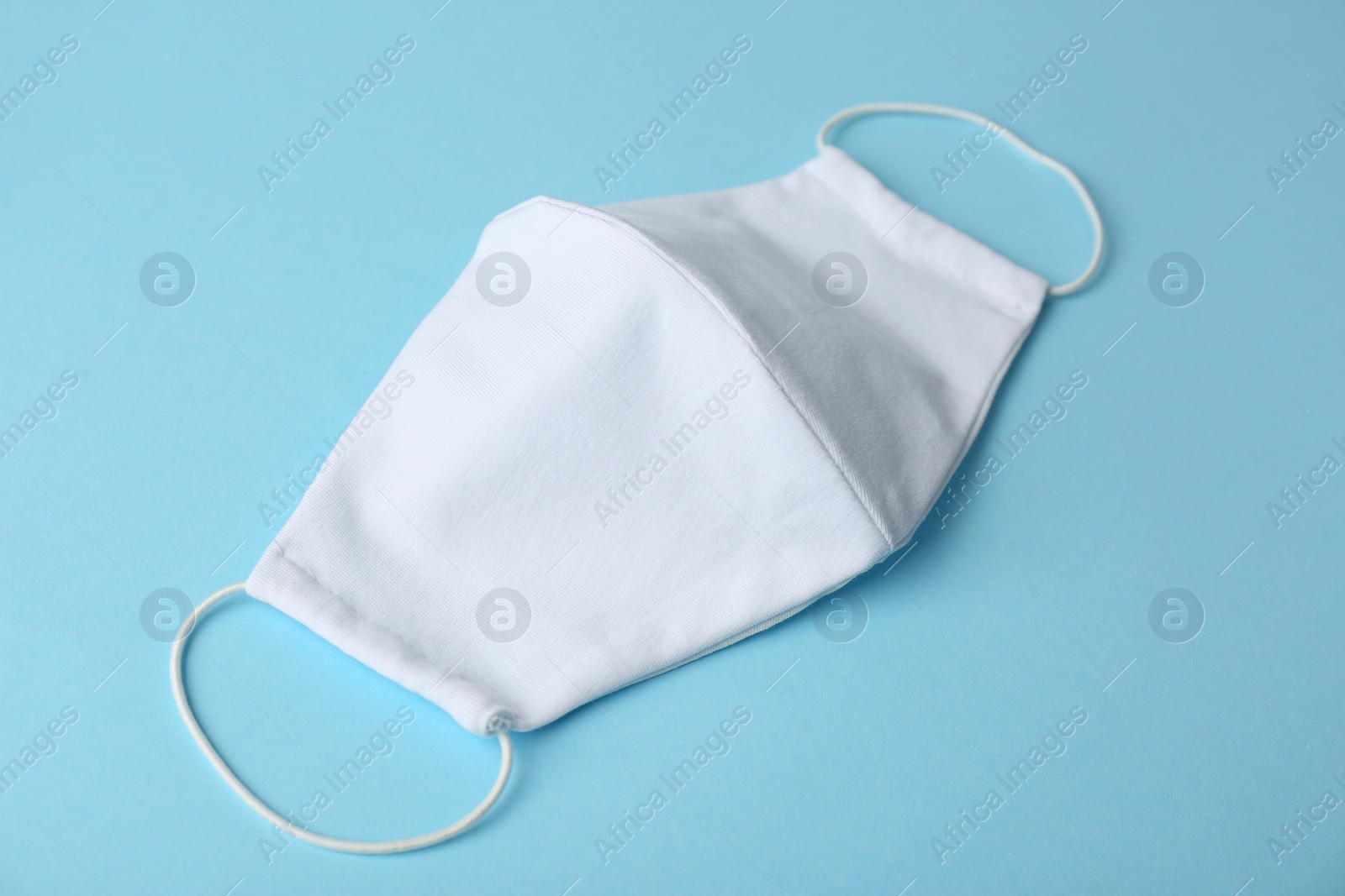 Photo of Homemade protective face mask on light blue background