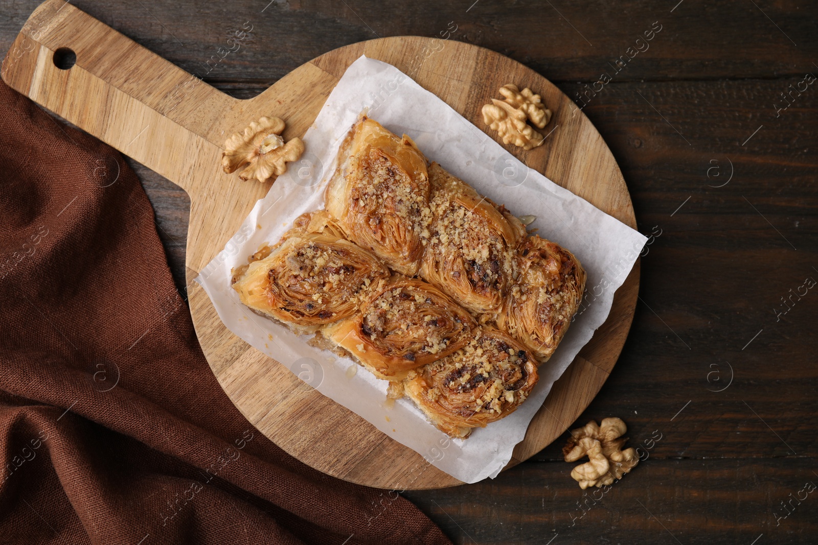 Photo of Eastern sweets. Pieces of tasty baklava and walnuts on wooden table, top view