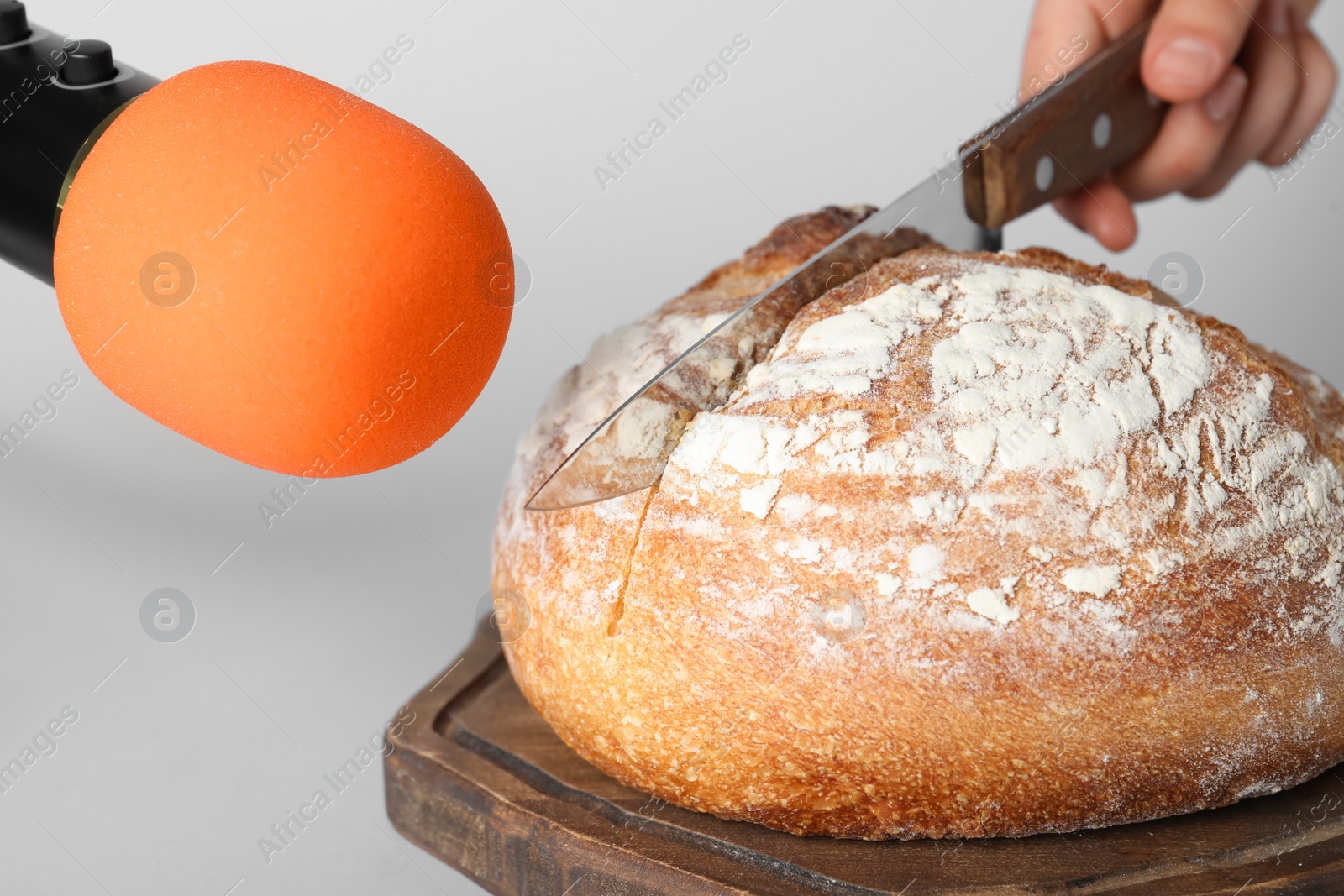 Photo of Woman making ASMR sounds with microphone and bread on grey background, closeup