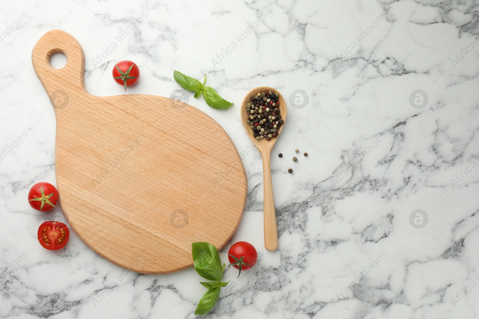 Photo of Cutting board, basil, spices and tomatoes on white marble table, flat lay. Space for text