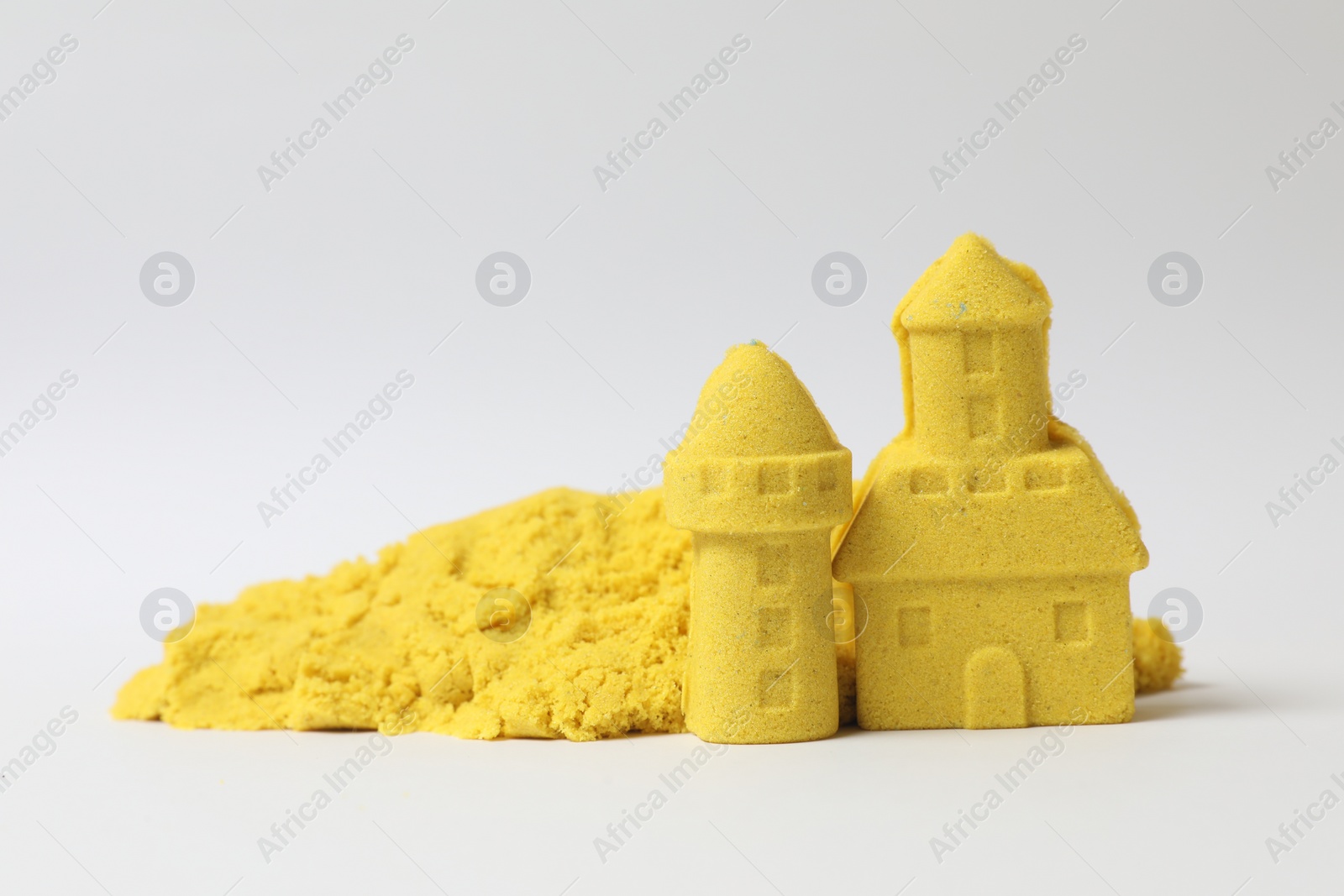 Photo of Castle and tower made of yellow kinetic sand on white background