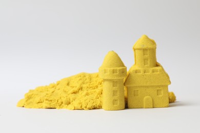 Photo of Castle and tower made of yellow kinetic sand on white background