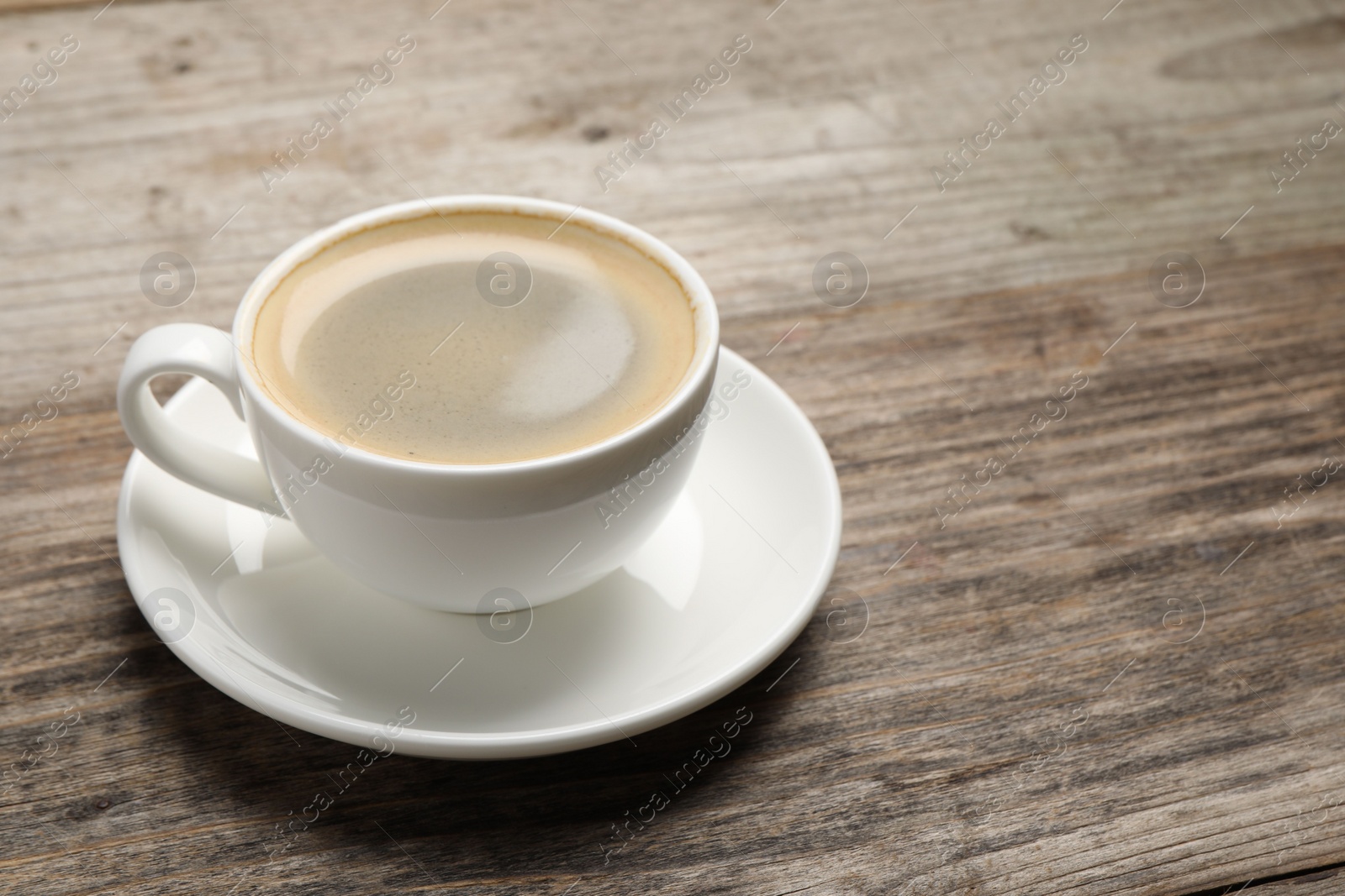 Photo of Aromatic coffee in cup on wooden table. Space for text