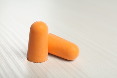 Photo of Pair of ear plugs on white wooden background, closeup