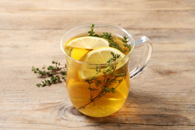 Photo of Aromatic herbal tea with thyme and lemon on wooden table