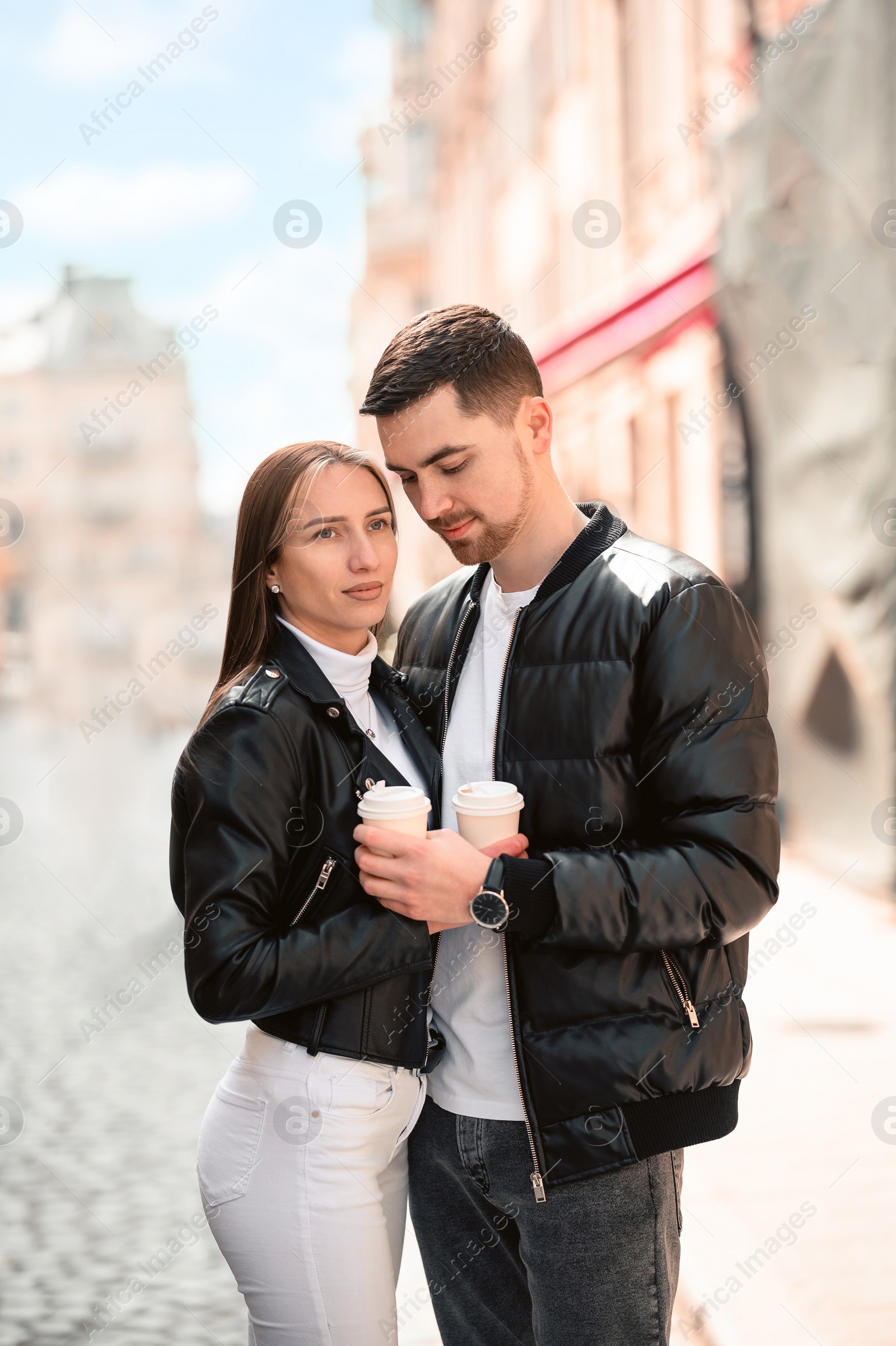 Photo of Lovely young couple with cups of coffee together on city street. Romantic date