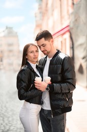 Lovely young couple with cups of coffee together on city street. Romantic date