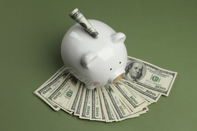 Photo of Money exchange. Dollar banknotes and piggy bank on green background