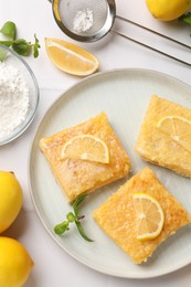 Tasty lemon bars with mint on white table, flat lay