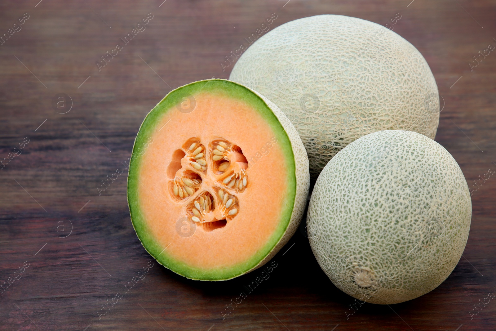 Photo of Whole and cut fresh ripe melons on wooden table