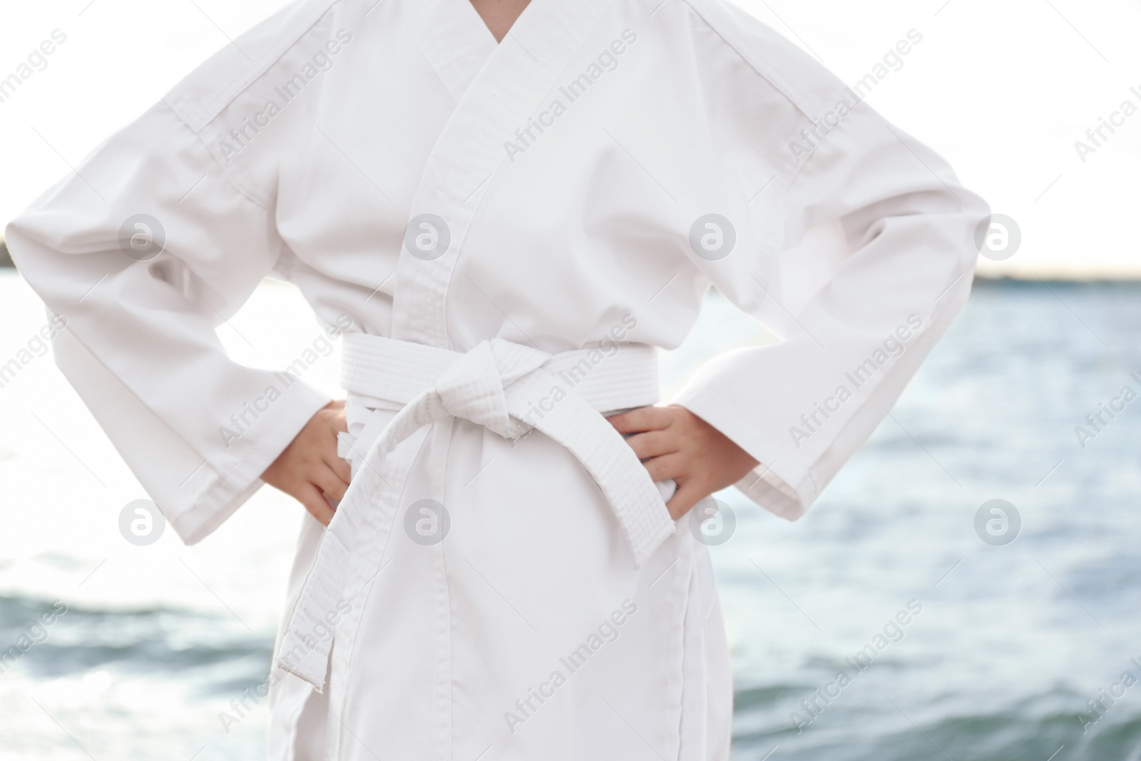 Photo of Cute little girl in kimono near river, closeup. Karate practicing