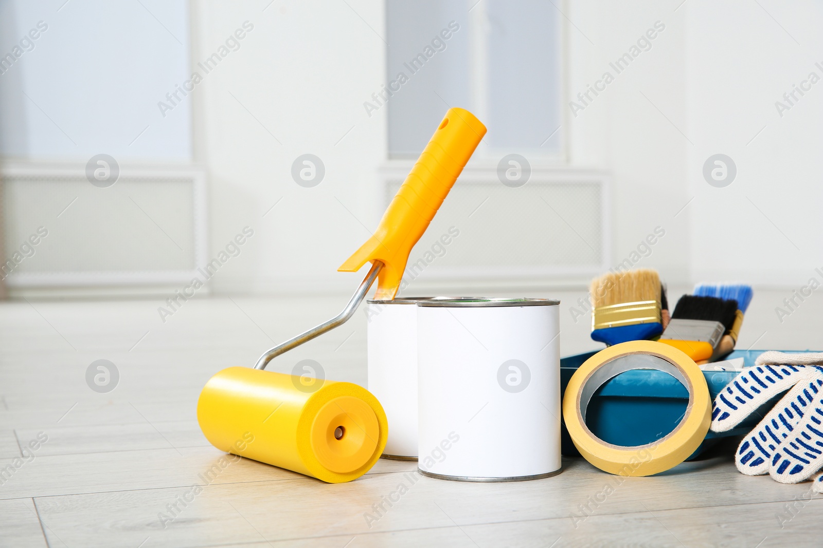 Photo of Cans of paint and decorator tools on wooden floor indoors