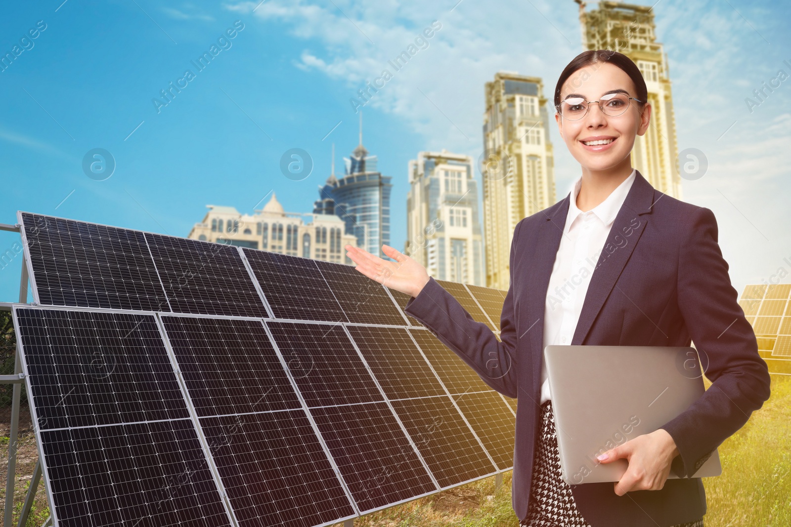 Image of Young businesswoman with laptop near solar panels and beautiful view of cityscape. Alternative energy source