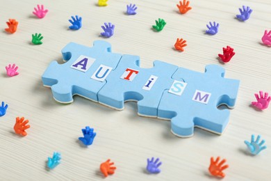 Composition with jigsaw puzzle pieces and word Autism on white wooden background