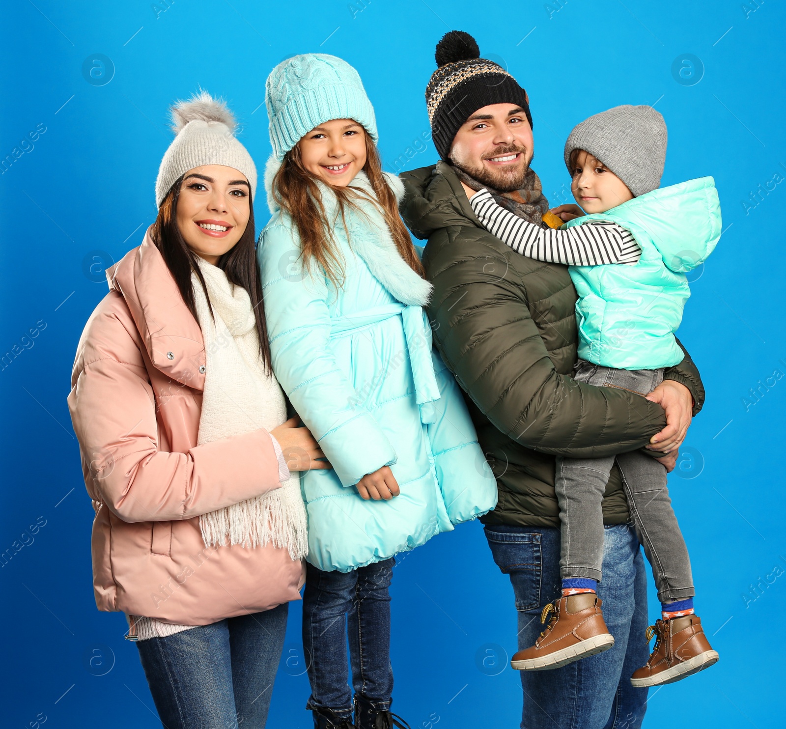 Photo of Happy family in warm clothes on blue background. Winter vacation