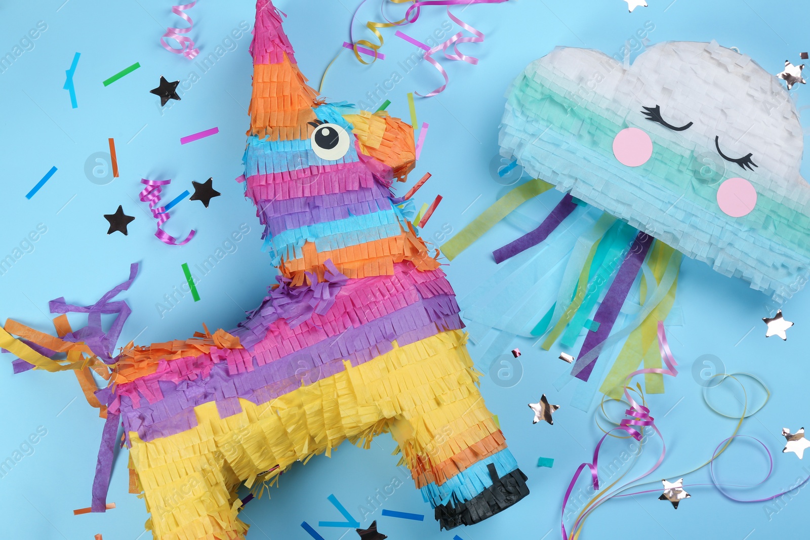 Photo of Different bright pinatas on light blue background, flat lay